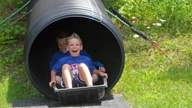 two campers from YMCA Camp Potawotami going down the mole hole slide